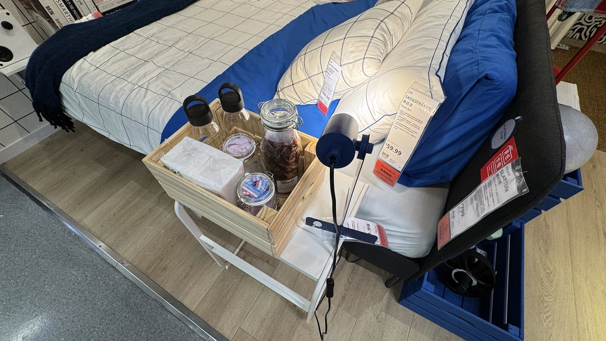 At the bedside: a pine box on the side table and a blue work lamp
