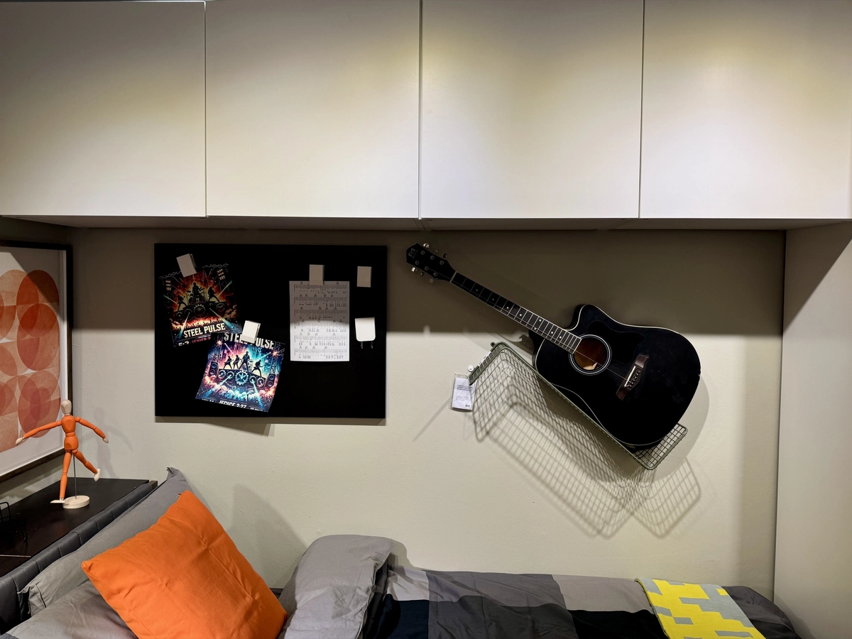 Wall cabinets, pinboard and guitar over the bed